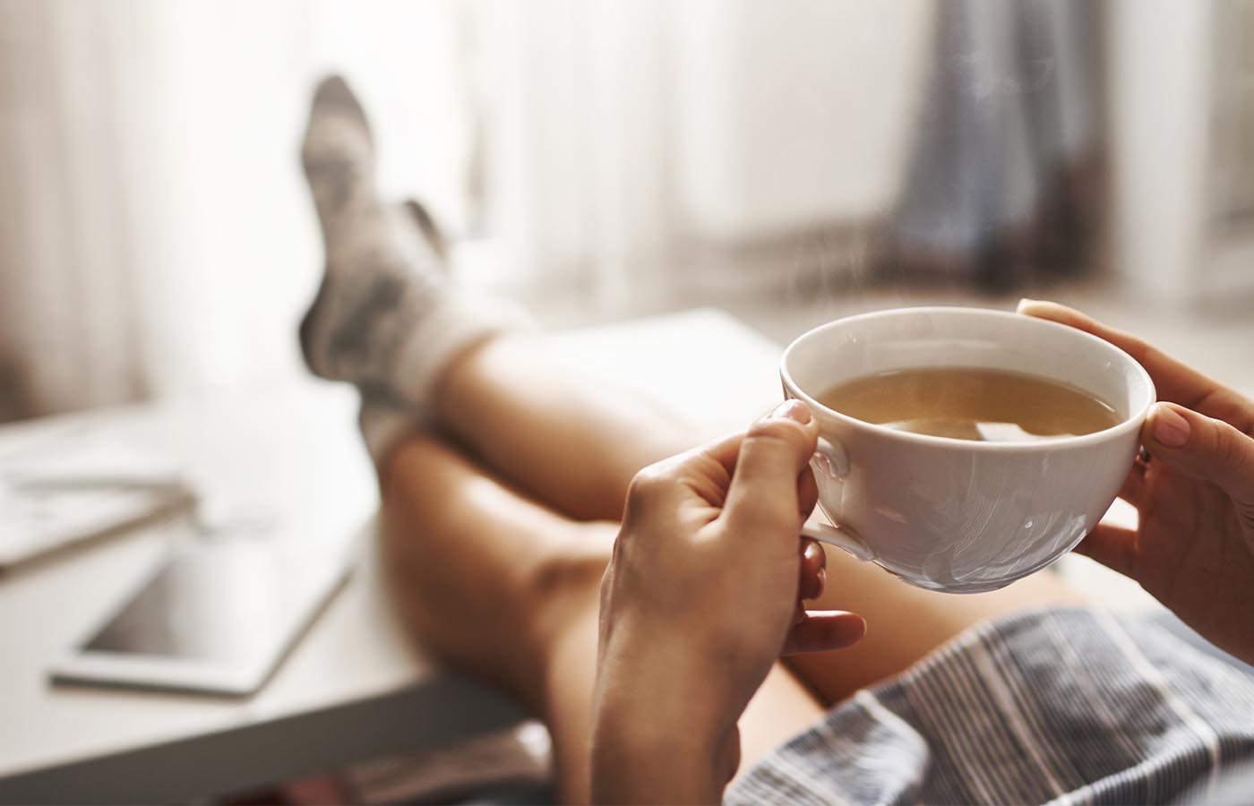 A woman relaxing on the couch with a cup of tea